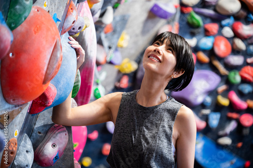 Portrait of a beautiful Asian woman smiling in front of a wall in a bouldering gym photo