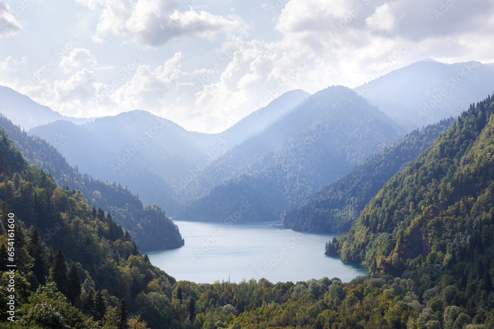 View of the lake in the mountains. Clouds and forest are reflected in the lake