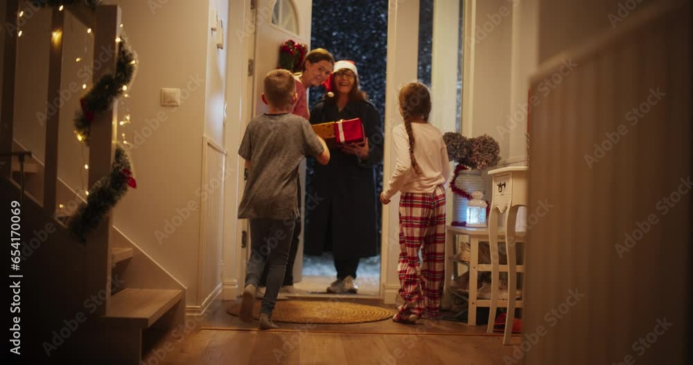Family Celebrating Winter Holidays Together. Small Son and Daughter Meeting Grandmother, Who Just Arrived with Festive Holiday Gifts. Grandparent Visiting Family for Christmas and New Year Family Celebrating Winter Holidays Together. Small Son and Daughter Meeting Grandmother, Who Just Arrived with Festive Holiday Gifts. Grandparent Visiting Family for Christmas and New Year