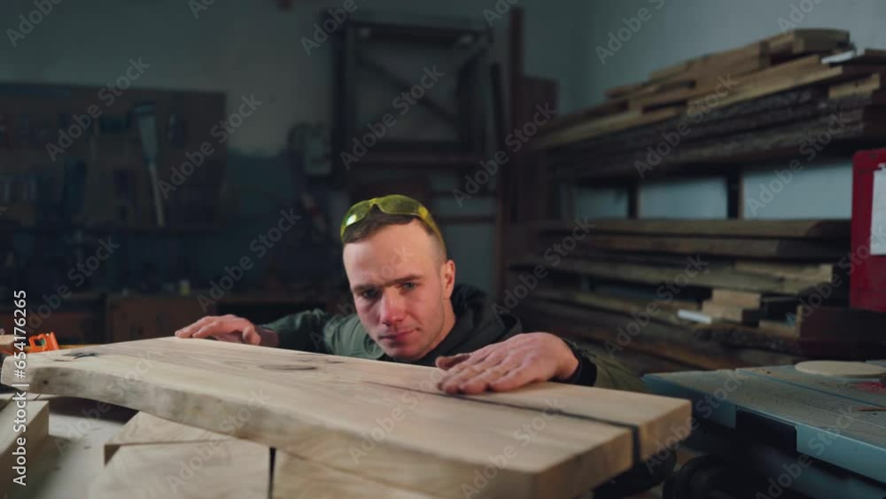 A focused carpenter in the carpenter checks the quality of the wood product. Joinery, small business. A focused carpenter in the carpenter checks the quality of the wood product. Joinery, small business.