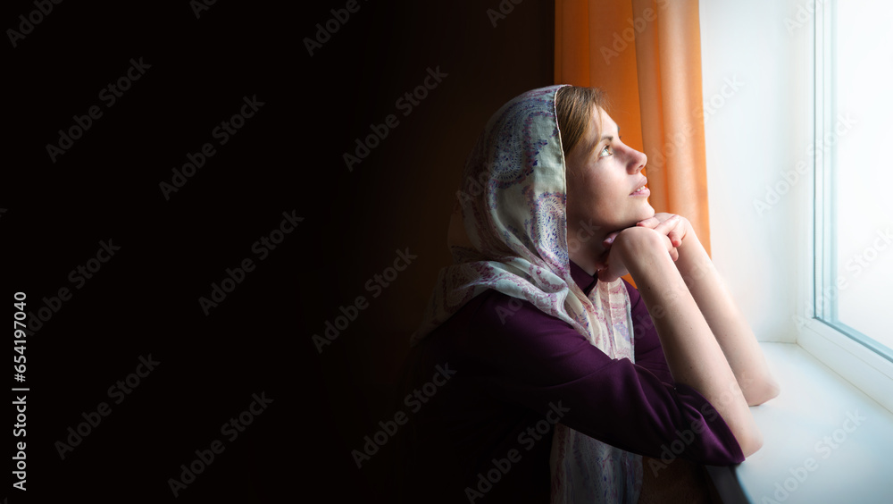 Girl praying by the window Girl praying by the window