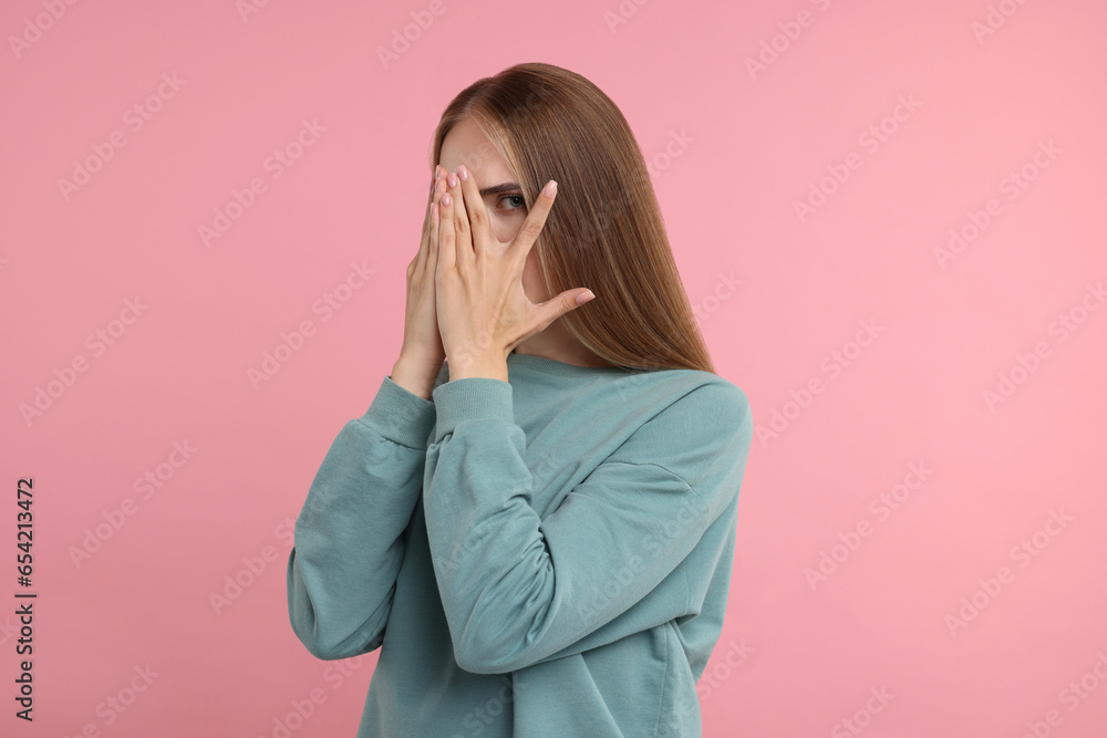 Embarrassed woman covering face with hands on pink background Embarrassed woman covering face with hands on pink background