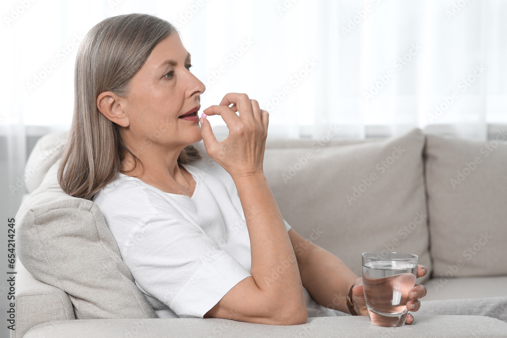 Senior woman with glass of water taking pill at home Senior woman with glass of water taking pill at home