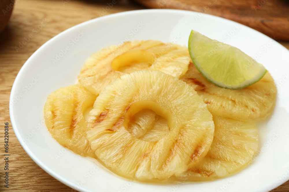 Tasty grilled pineapple slices and piece of lime on table, closeup Tasty grilled pineapple slices and piece of lime on table, closeup