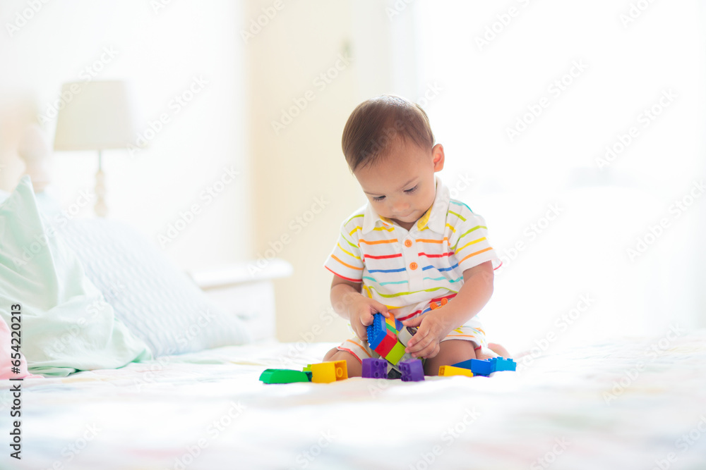 Baby boy playing on bed in sunny nursery Baby boy playing on bed in sunny nursery