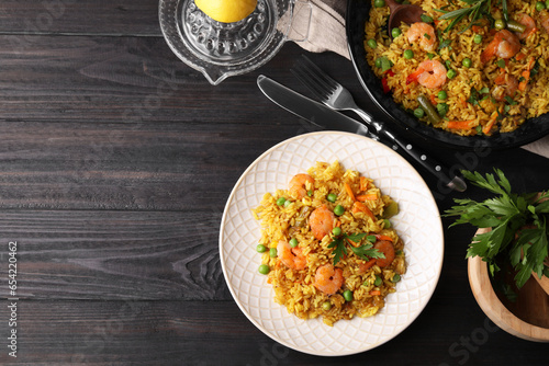 Tasty rice with shrimps and vegetables served on dark wooden table, flat lay. Space for text