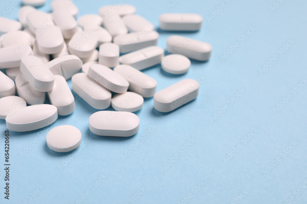 Many pills on light blue background, closeup. Space for text Many pills on light blue background, closeup. Space for text