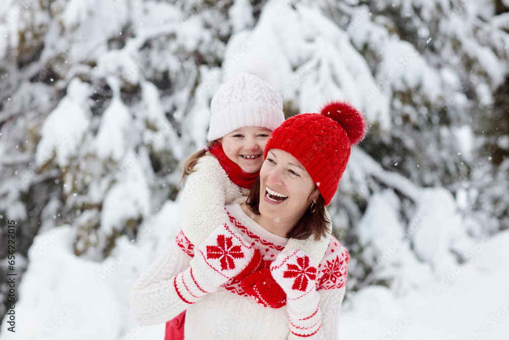Mother and child in knitted winter hats in snow.