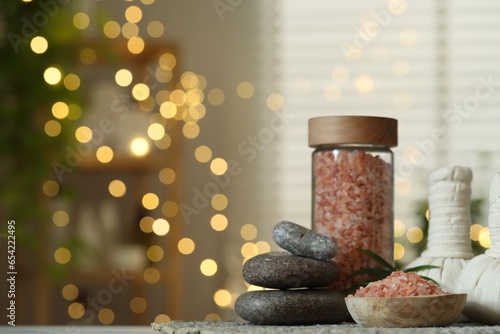 Spa composition. Herbal bags, sea salt and stones on table indoors, space for text