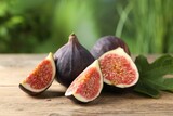 Fresh ripe figs and green leaf on wooden table, closeup