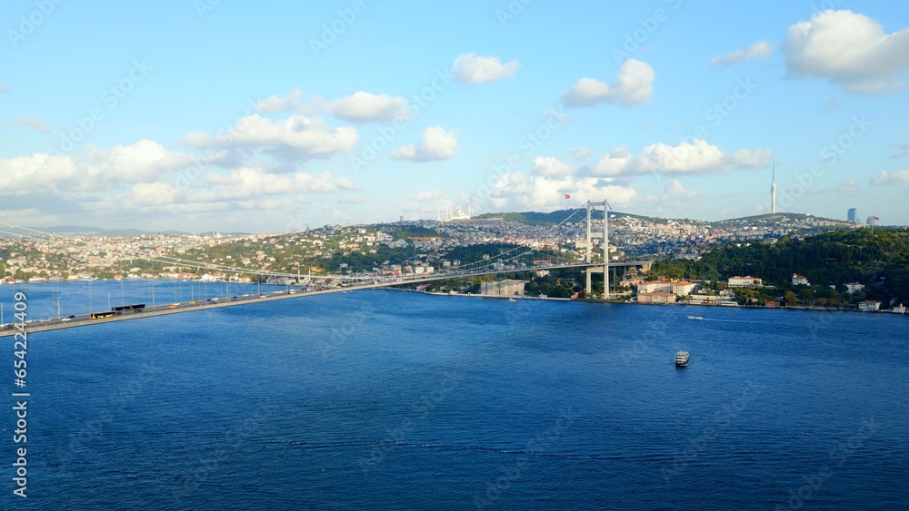 Bird's eye view of Bosphorus Bridge. Aerial drone view. View of the Asian part of Istanbul. The city and the Turkish flag can be seen in the distance.