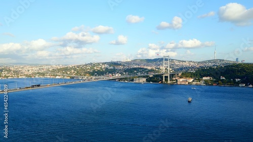 Bird's eye view of Bosphorus Bridge. Aerial drone view. View of the Asian part of Istanbul. The city and the Turkish flag can be seen in the distance. © JackDaniProduction