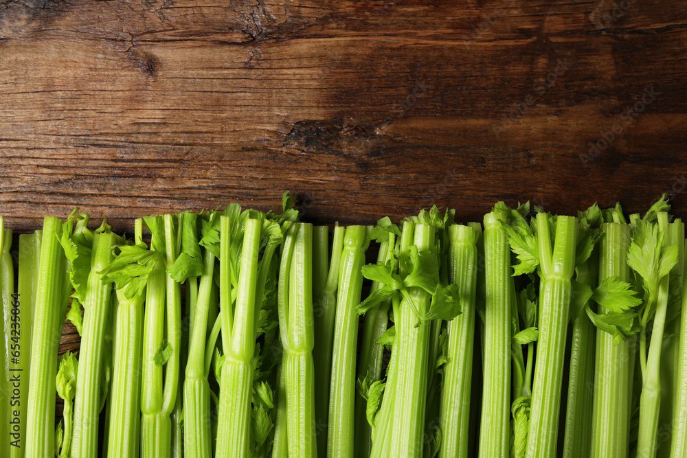 Fresh ripe green celery on wooden table, flat lay. Space for text