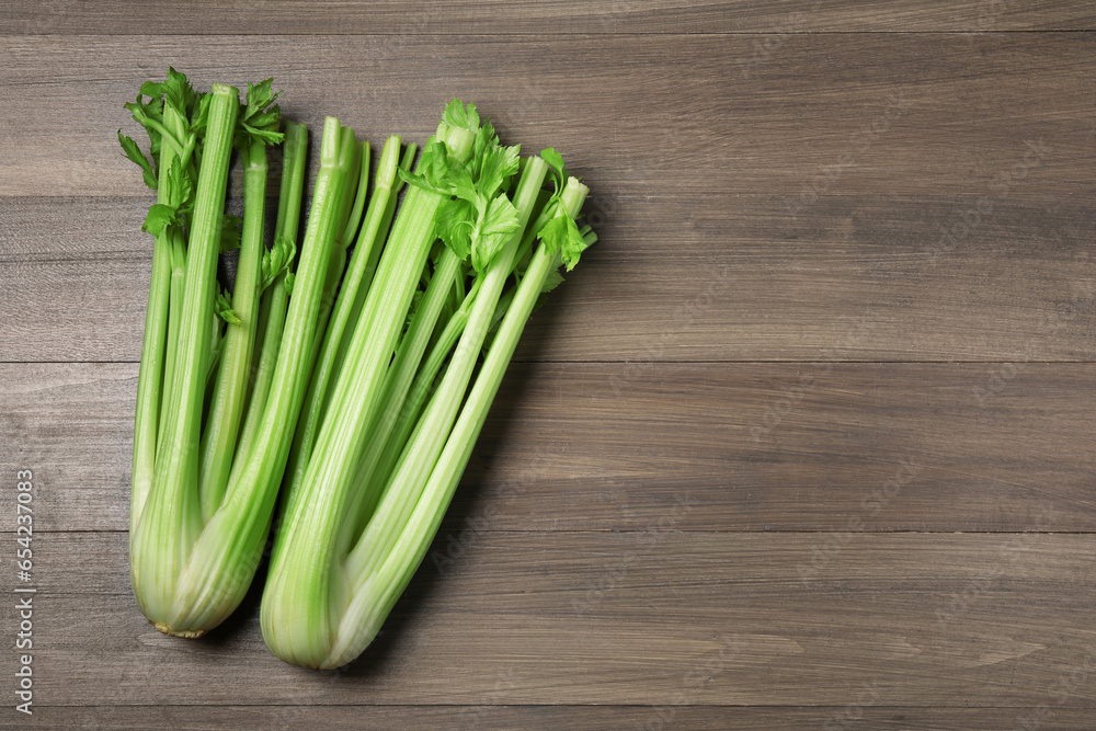 Fresh green celery stalks on wooden table, flat lay. Space for text
