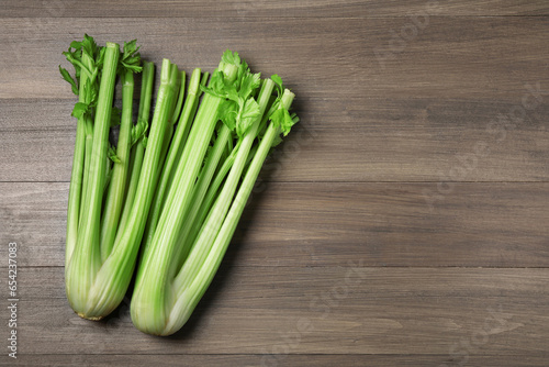 Fresh green celery stalks on wooden table, flat lay. Space for text
