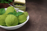 Tasty matcha ice cream and spoon with powder in bowl on brown table, closeup. Space for text