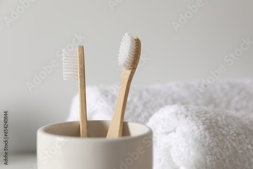 Holder with bamboo toothbrushes on blurred background, closeup. Space for text