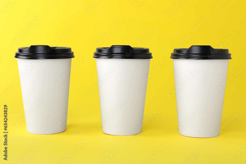 Paper cups with black lids on yellow background. Coffee to go Paper cups with black lids on yellow background. Coffee to go