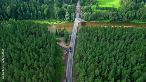 Road Under Construction Between a Green Forest and Brown Murky River from an Aerial Drone Shot in Latvia. photo