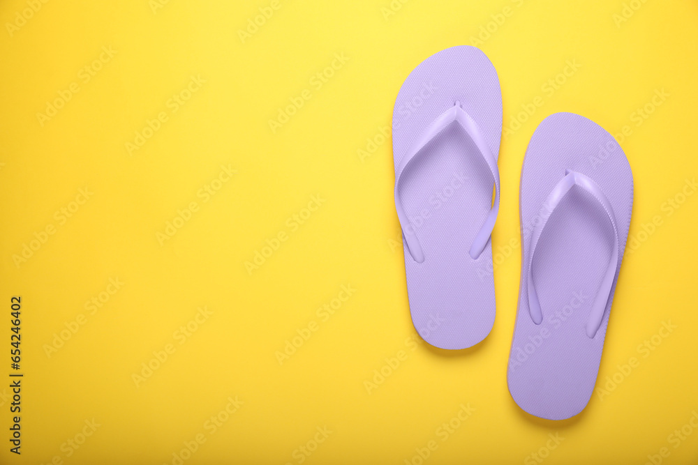 Stylish violet flip flops on yellow background, top view. Space for text Stylish violet flip flops on yellow background, top view. Space for text