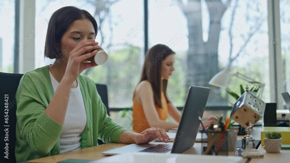Focused woman drinking coffee typing laptop cabinet closeup. Startupers working Focused woman drinking coffee typing laptop cabinet closeup. Startupers working