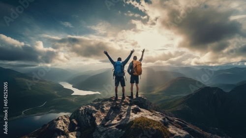 Happy two hikers with raised arms on top of the mountain photo