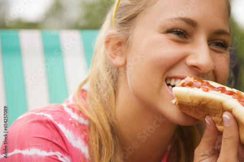 Close up of a teenaged girl eating a hot dog
