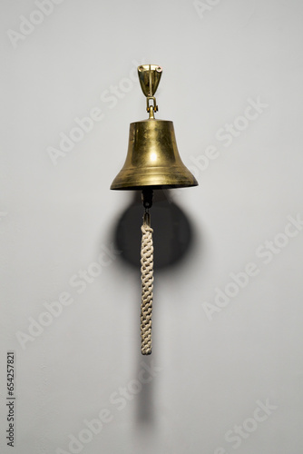 Brass bell with rope pull hanging on wall
 photo