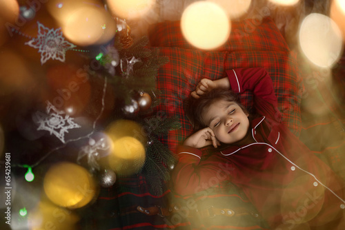 6 years old girl in red pajamas sleeping in bed in holiday lights