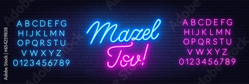 Mazel Tov neon lettering on brick wall background.