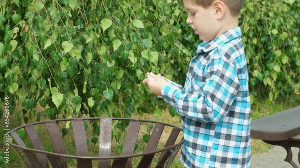 A small child throws paper trash into the trash bin. Garbage sorting and recycling concept. A small child throws paper trash into the trash bin. Garbage sorting and recycling concept.