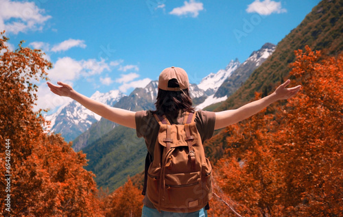 Girl with a backpack stands with her back and looks into the distance at the mountains. Active lifestyle, travel that inspires. Autumn landscape