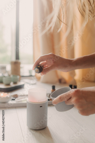 Air humidifier, calm blurred woman, girl practice meditation do yoga exercise at home. Aromatherapy steam scent from essential oil diffuser in living room at home