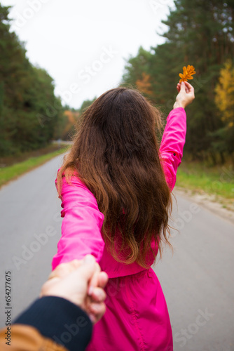the girl is standing on the road holding a yellow leaf