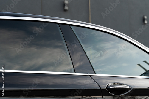 Exterior of executive luxury car of black color with tinted windows standing at parking outdoors. Modern design of expensive automobile