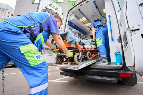 Paramedic in a protective mask unloads a patient from an ambulance