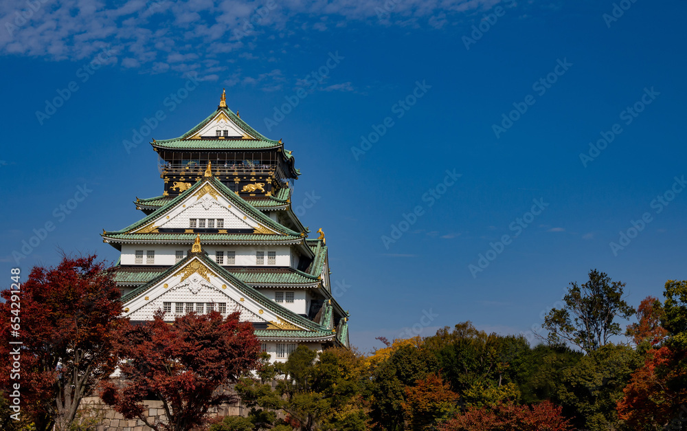 Main Tower of Osaka Castle in Autumn with red orange green leaves, blue sky backgroung Main Tower of Osaka Castle in Autumn with red orange green leaves, blue sky backgroung