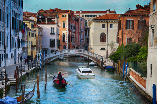 Venice, Italy - March 14 2016: Impression gondola ride with gondolier along a Canal in Venice, beautiful view of bridge and old buildings in Venice, gondola and a boat ride along a canal