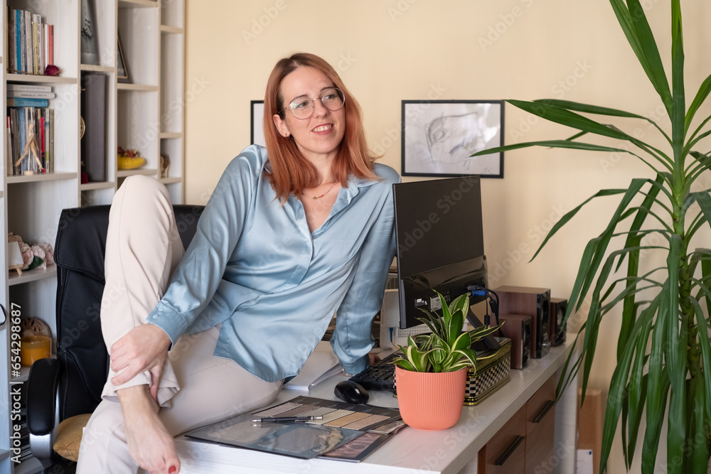 Adult business woman portrait by her home office sitting on a desk 