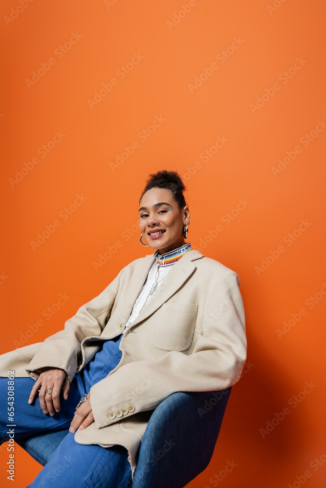 happy smiling african american woman in fashionable outfit sitting on chair and smiling at camera happy smiling african american woman in fashionable outfit sitting on chair and smiling at camera