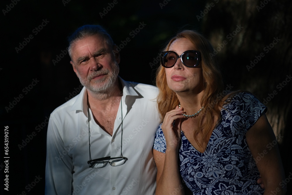 Obraz premium Portrait of a woman and a man. A couple. A woman with long blond hair. The woman is dressed in a blue dress. Silver necklace. The man is dressed in a white shirt.