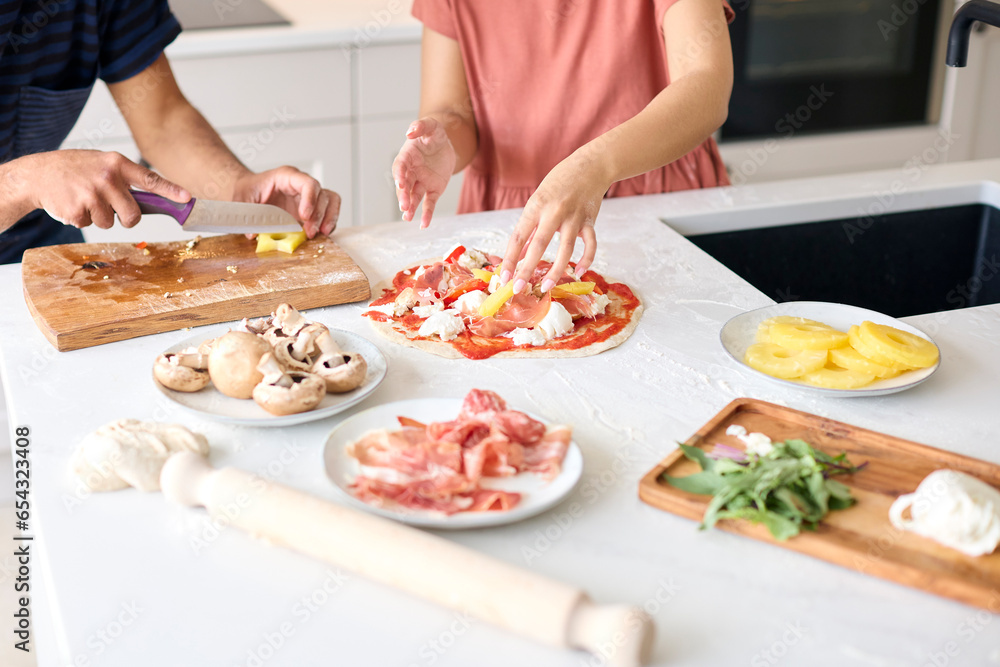 Close Up Of Couple At Home Putting Toppings On Pizza In Kitchen Together