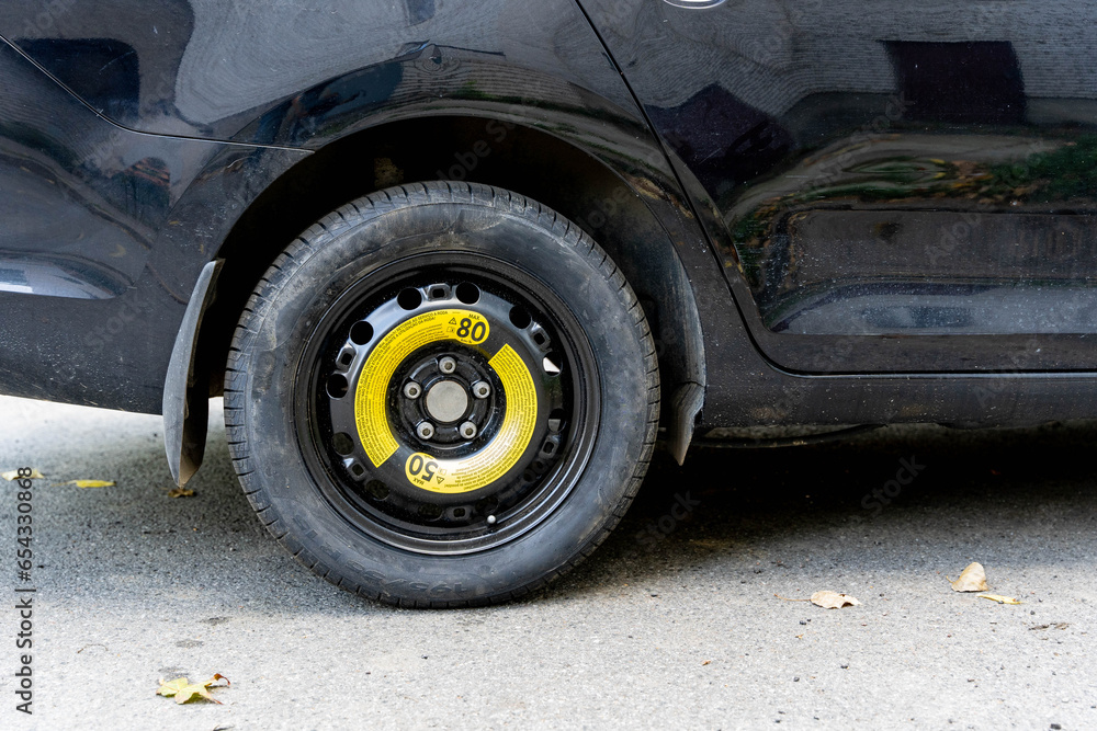 a black passenger car with a spare wheel installed is parked on the road