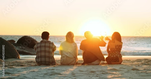 Four Friends on the Beach Watching the Sunset and Raising Glasses