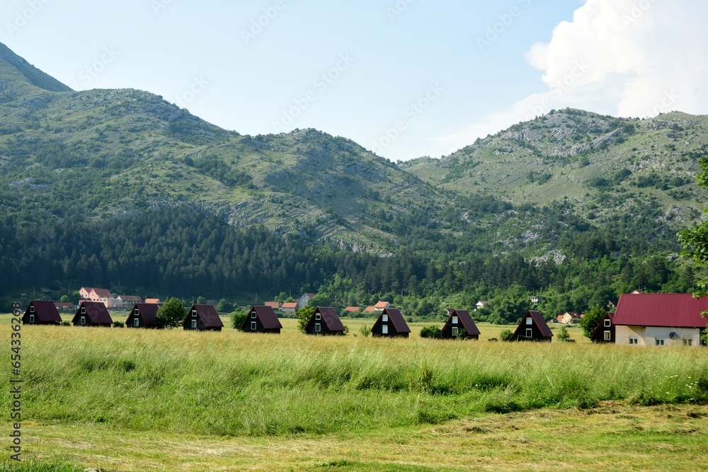 Obraz premium Montenegro LANDSCAPE WITH WOODEN TOURIST HOUSES ON THE BACKGROUND OF MOUNTAINS, CAMPING, HOTEL