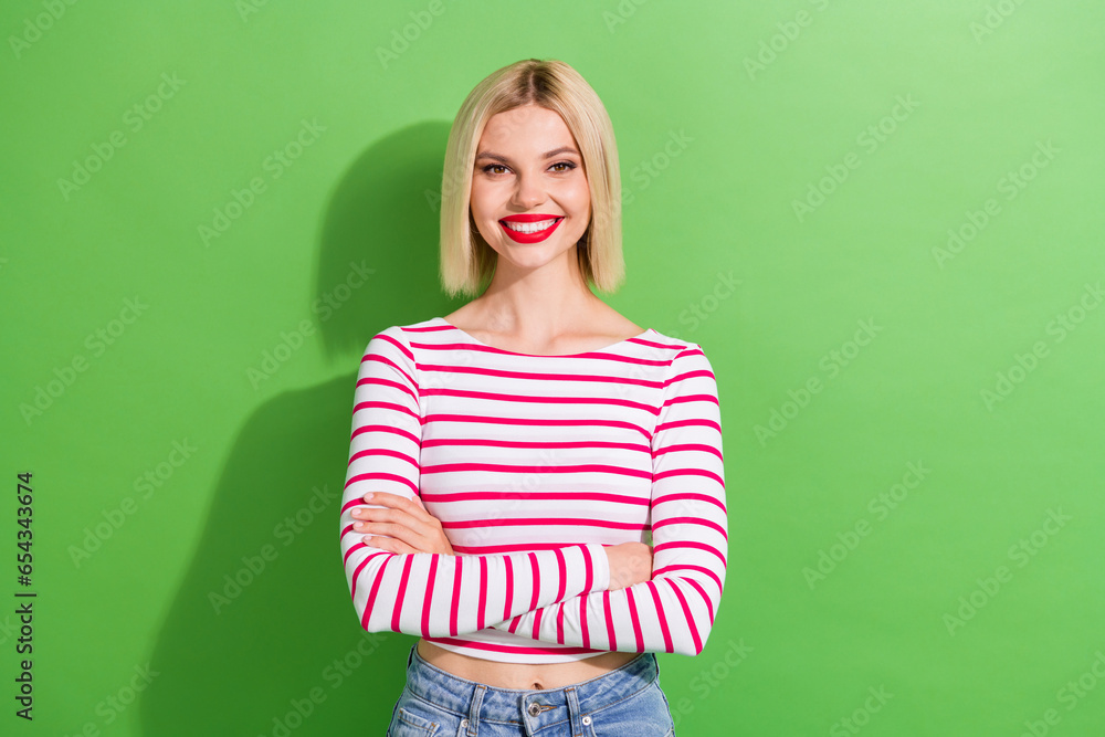 Portrait of pleasant pretty girl with short hairdo dressed striped clothes holding arms folded smiling isolated on green color background Portrait of pleasant pretty girl with short hairdo dressed striped clothes holding arms folded smiling isolated on green color background