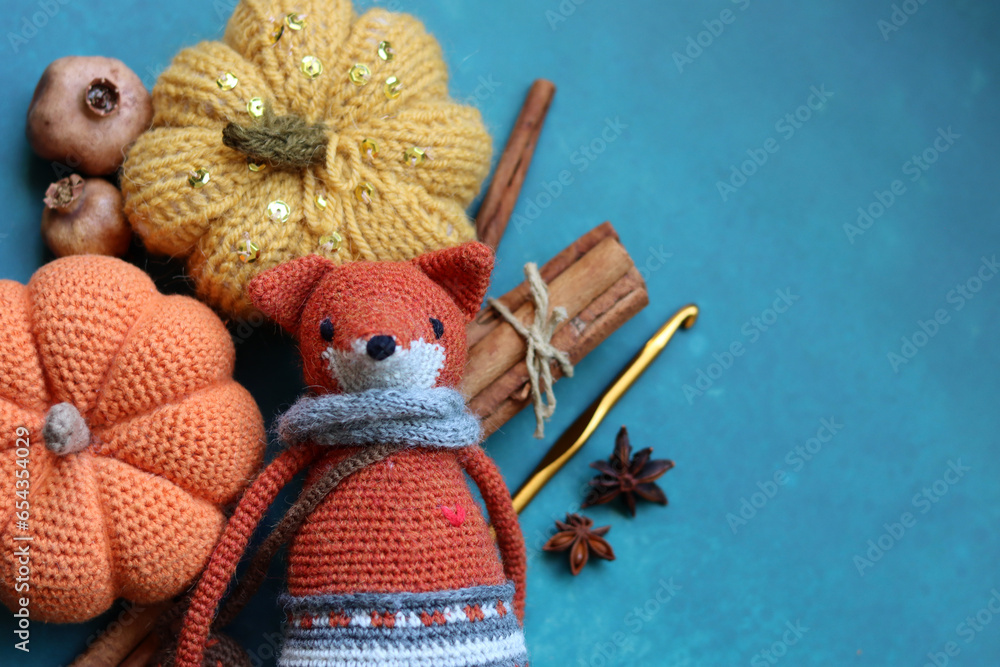 Fototapeta premium Knitted toy fox, yarn balls and autumn decorations on a gray background with space for text. Cute amigurumi toy. 