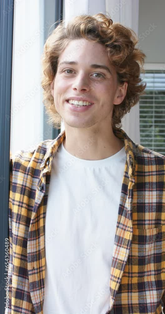Vertical video of portrait of happy caucasian man looking through window at home, slow motion Vertical video of portrait of happy caucasian man looking through window at home, slow motion