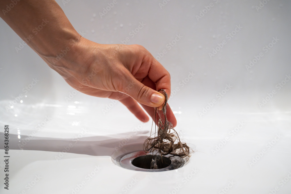 Water drain hole in bath is clogged with hair clump in bathroom at home