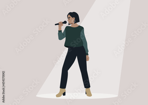A youthful, self-assured singer on a well-lit stage, holding a microphone beneath the spotlight